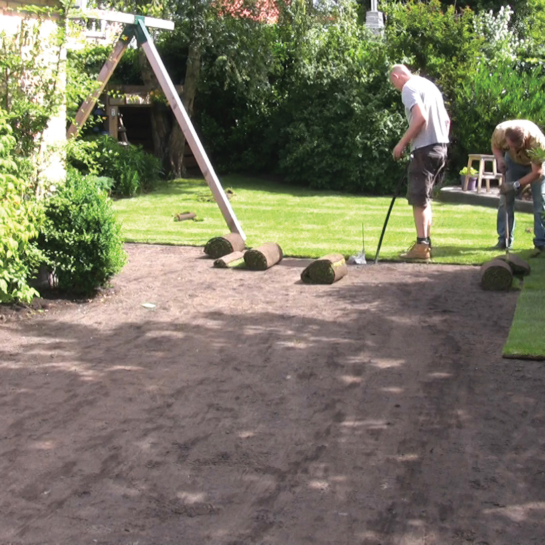 Kale, geëgaliseerde ondergrond in een achtertuin met opgerolde graszoden klaar om te leggen